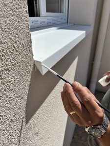 Últimos toques en la instalación de vierteaguas metálico instalado en ventana de fachada