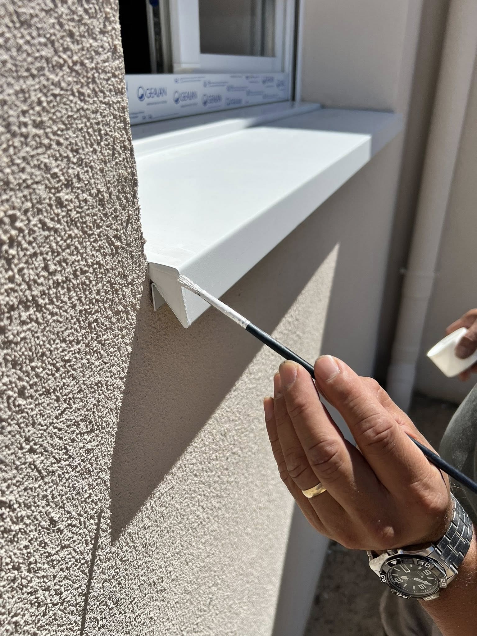 Últimos toques en la instalación de vierteaguas metálico instalado en ventana de fachada